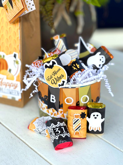 Decorated candy bowl with confetti and  Halloween candy inside and leaning against the bowl.