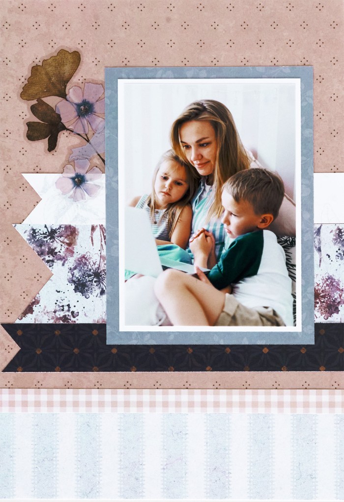 A woman sitting with two children, engrossed in a laptop, surrounded by decorative patterned scrapbook elements.
