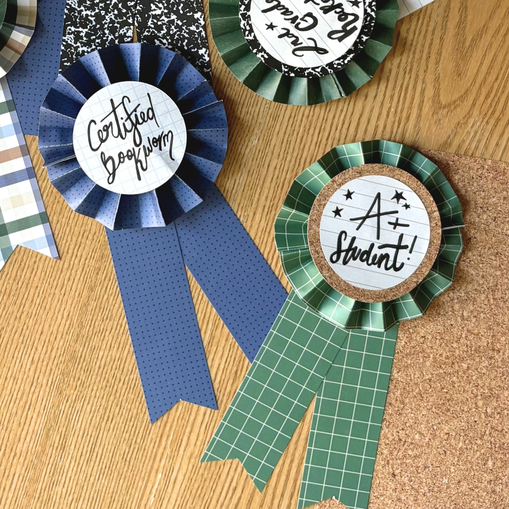 A collection of decorative award ribbons on a wooden surface, featuring phrases like 'Certified Bookworm' and 'A+ Student!' in playful typography.