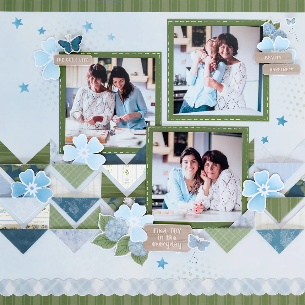 A blue and green scrapbook layout with three photos of a mother and daughter baking together, rows of folded designer paper chevrons, stenciled blue flowers and stars, and hydrangea stickers.
